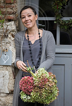 ROQUELIN, LOIRE VALLEY, FRANCE: OWNER ALINE CHASSINE WITH HYDRANGEAS OUTSIDE THE FRONT DOOR OF THE FARMHOUSE