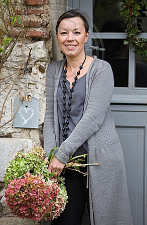 ROQUELIN, LOIRE VALLEY, FRANCE: OWNER ALINE CHASSINE WITH HYDRANGEAS OUTSIDE THE FRONT DOOR OF THE FARMHOUSE